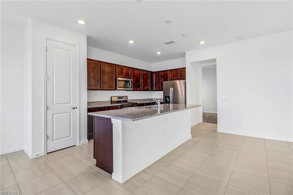 2167 Yellowfin Circle Naples, FL 34114 - Photo 7 of 36 a kitchen with stainless steel appliances a refrigerator and a stove top oven