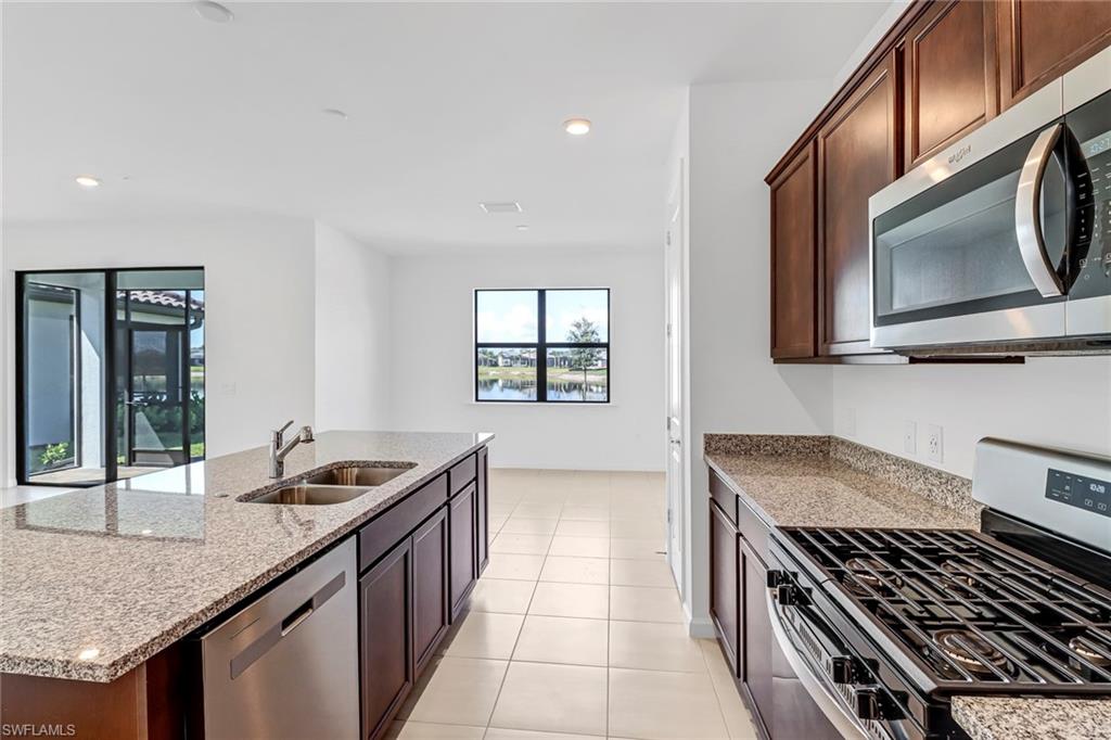 2167 Yellowfin Circle Naples, FL 34114 - Photo 8 of 36 a kitchen with stainless steel appliances granite countertop a stove and a microwave