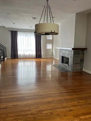 a view of an empty room with window and wooden floor