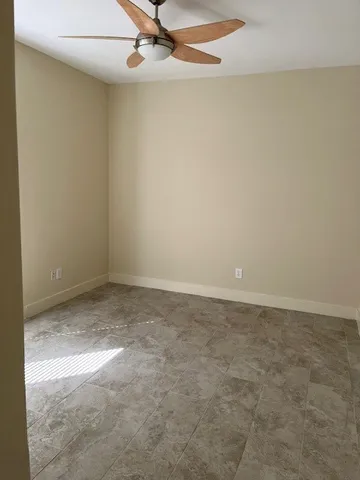 an empty room with a ceiling fan and carpet