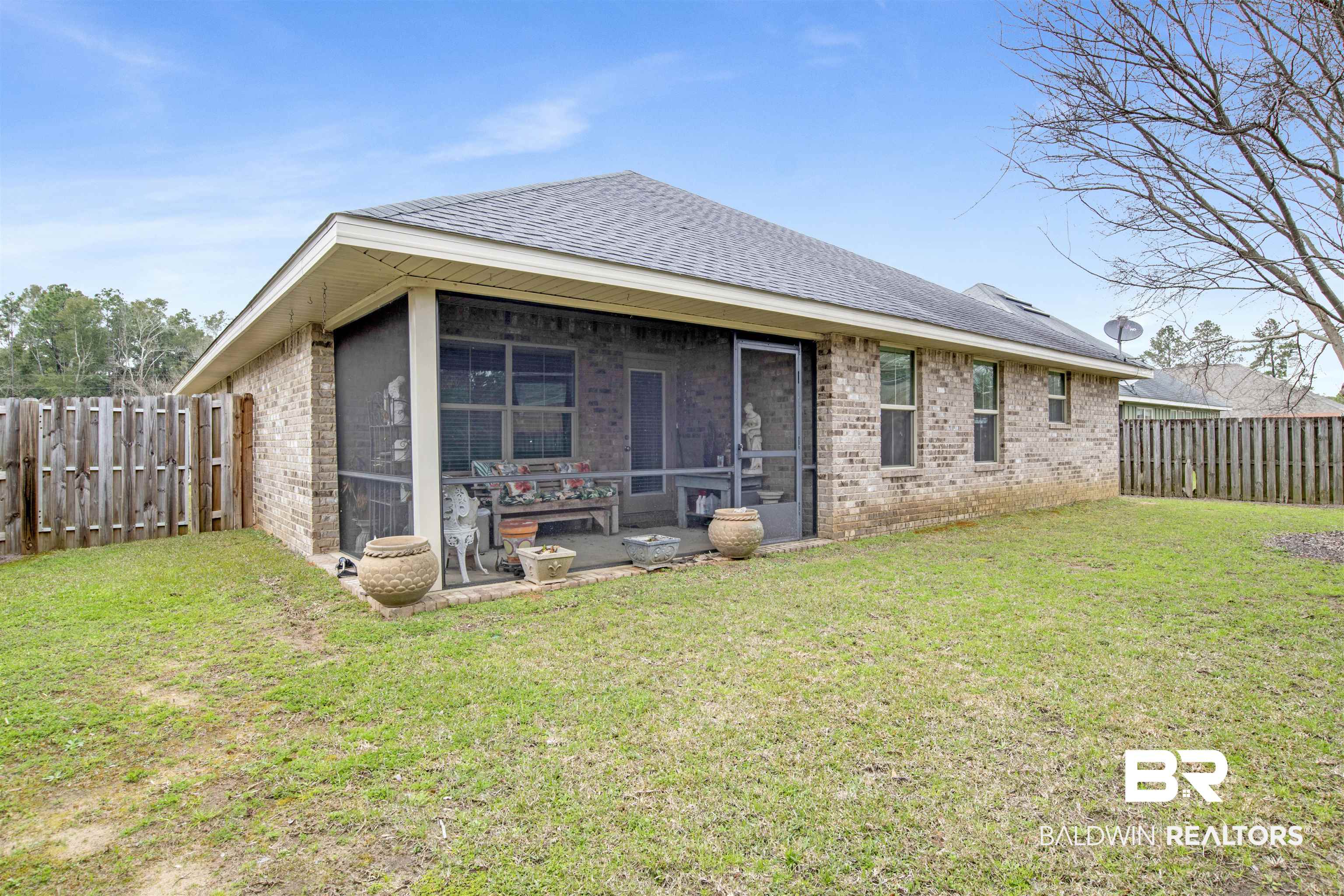 22056 Garland Loop Silverhill, AL 36576 - Photo 22 of 28 Back of property featuring a sunroom, a fenced backyard, brick siding, a shingled roof, and a lawn