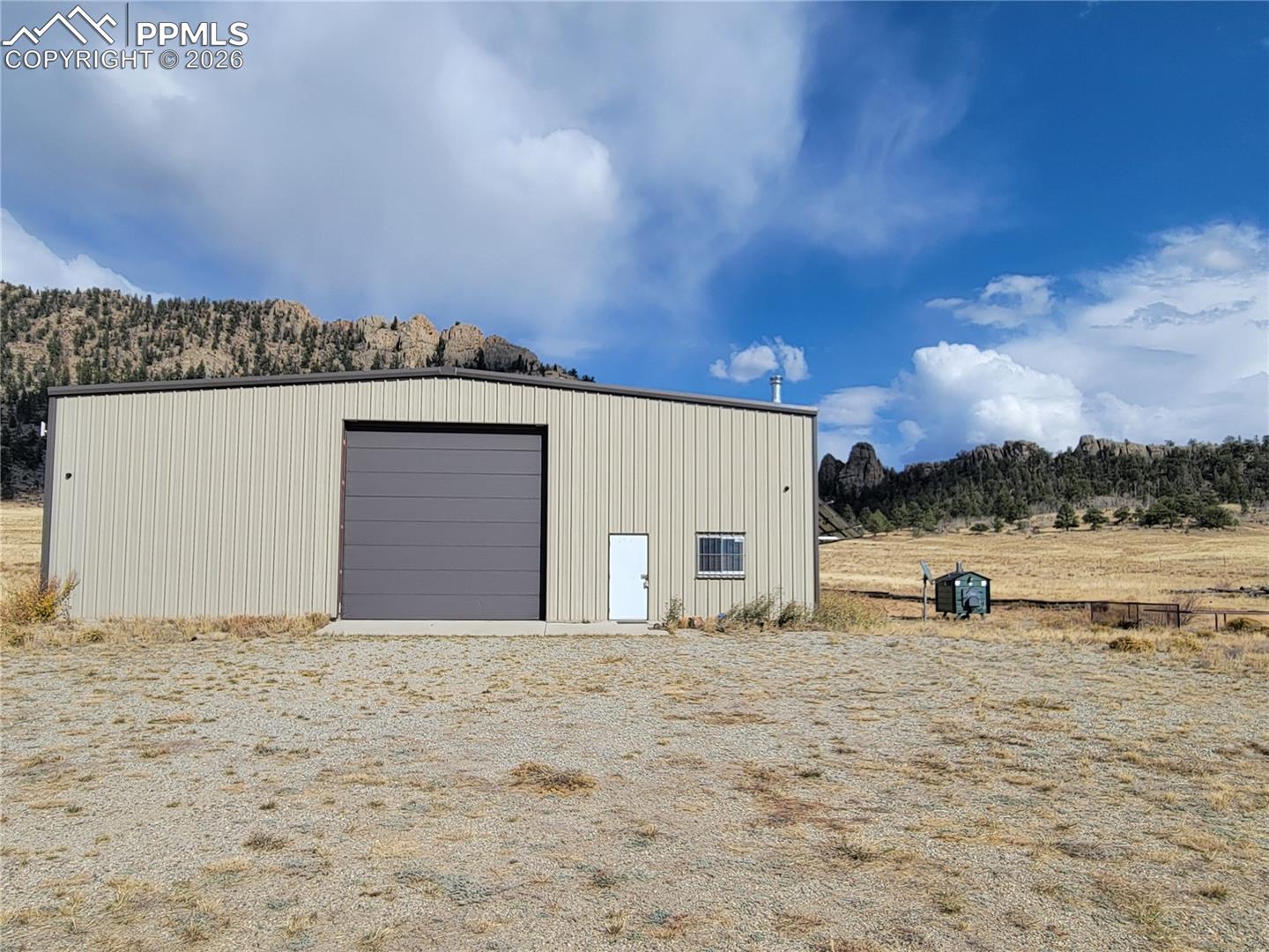 940 Puma Hills Road Lake George, CO 80827 - Photo 1 of 42 The property features a 60x60 metal building with a roll-up garage door and an entry door, set against a Pike National Forest