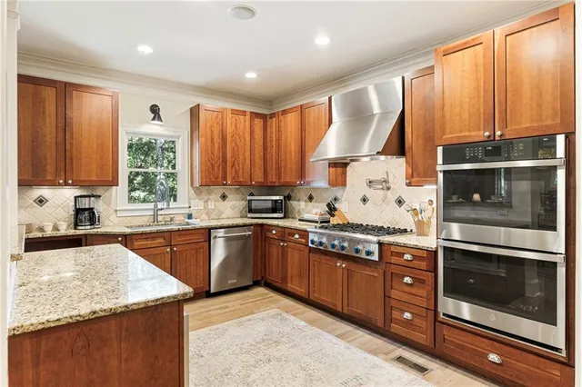 a kitchen with stainless steel appliances granite countertop wooden cabinets a sink and a stove