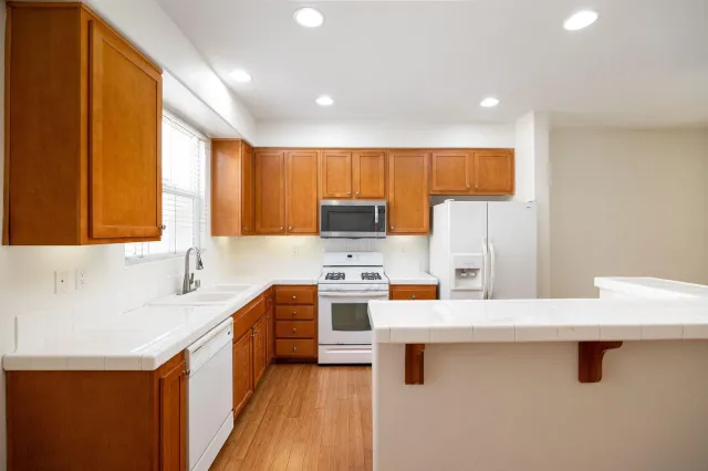 a kitchen with stainless steel appliances a stove a sink and a refrigerator with wooden floor