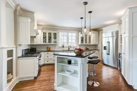 a kitchen with stainless steel appliances a stove a sink dishwasher and white cabinets with wooden floor