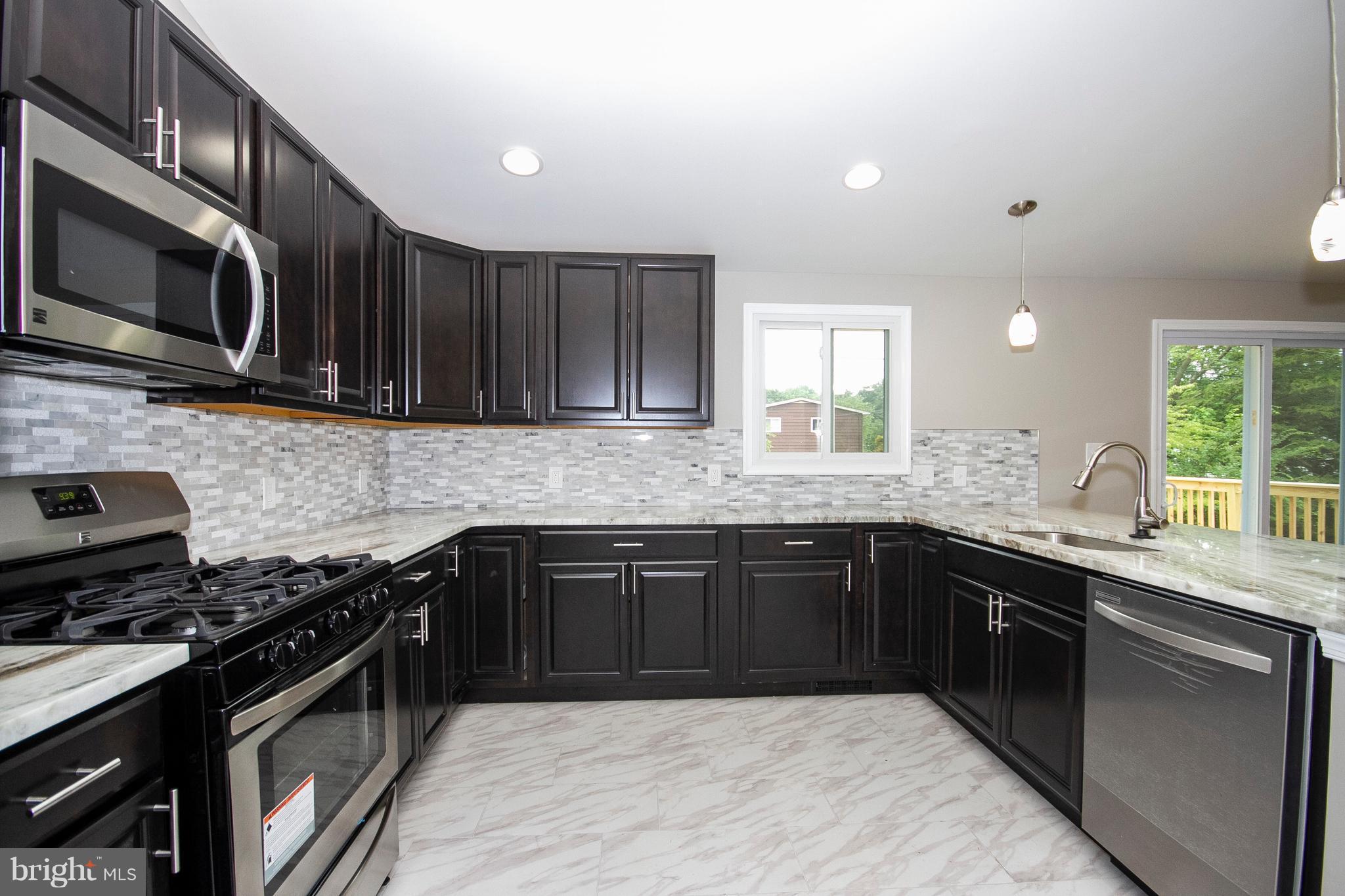 7412 Prince George Road Baltimore, MD 21208 - Photo 1 of 22 a kitchen with stainless steel appliances granite countertop wooden cabinets a stove top oven a sink and dishwasher
