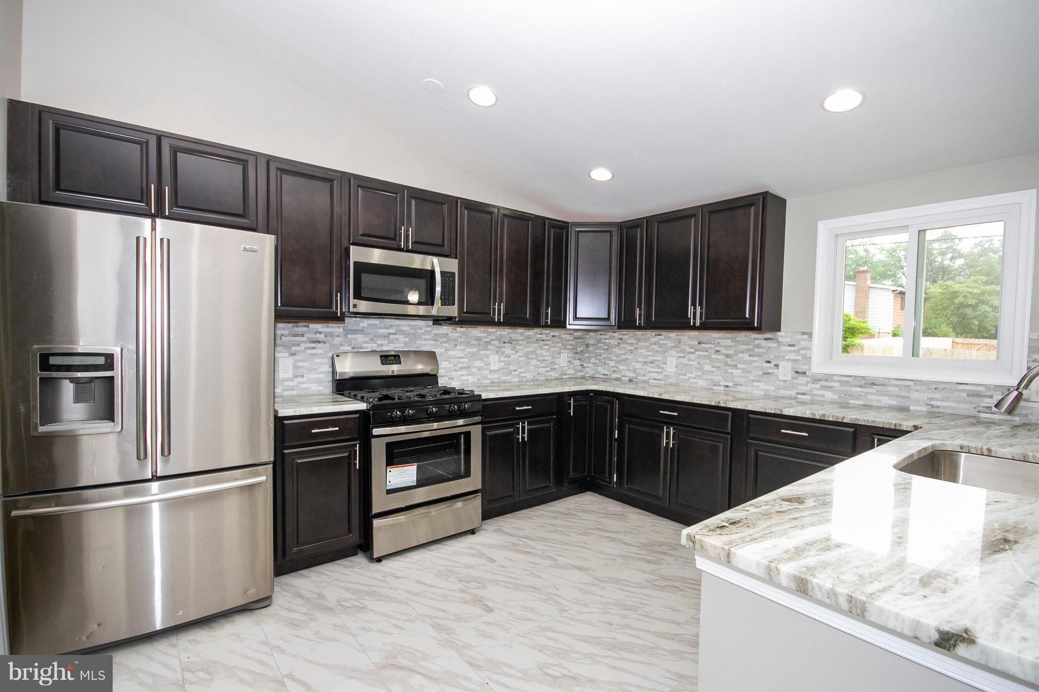 7412 Prince George Road Baltimore, MD 21208 - Photo 2 of 22 a kitchen with granite countertop wooden cabinets a refrigerator and a sink