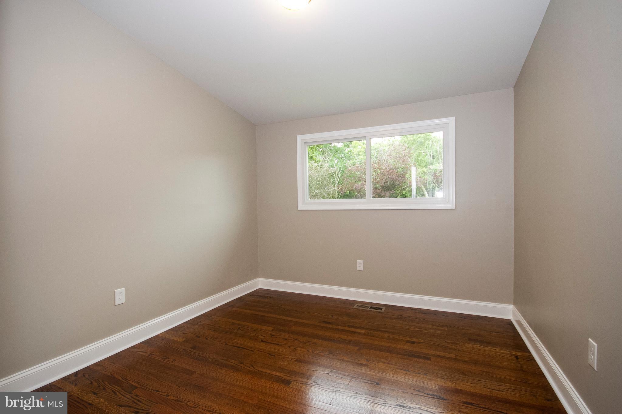 7412 Prince George Road Baltimore, MD 21208 - Photo 11 of 22 a view of an empty room with wooden floor and a window