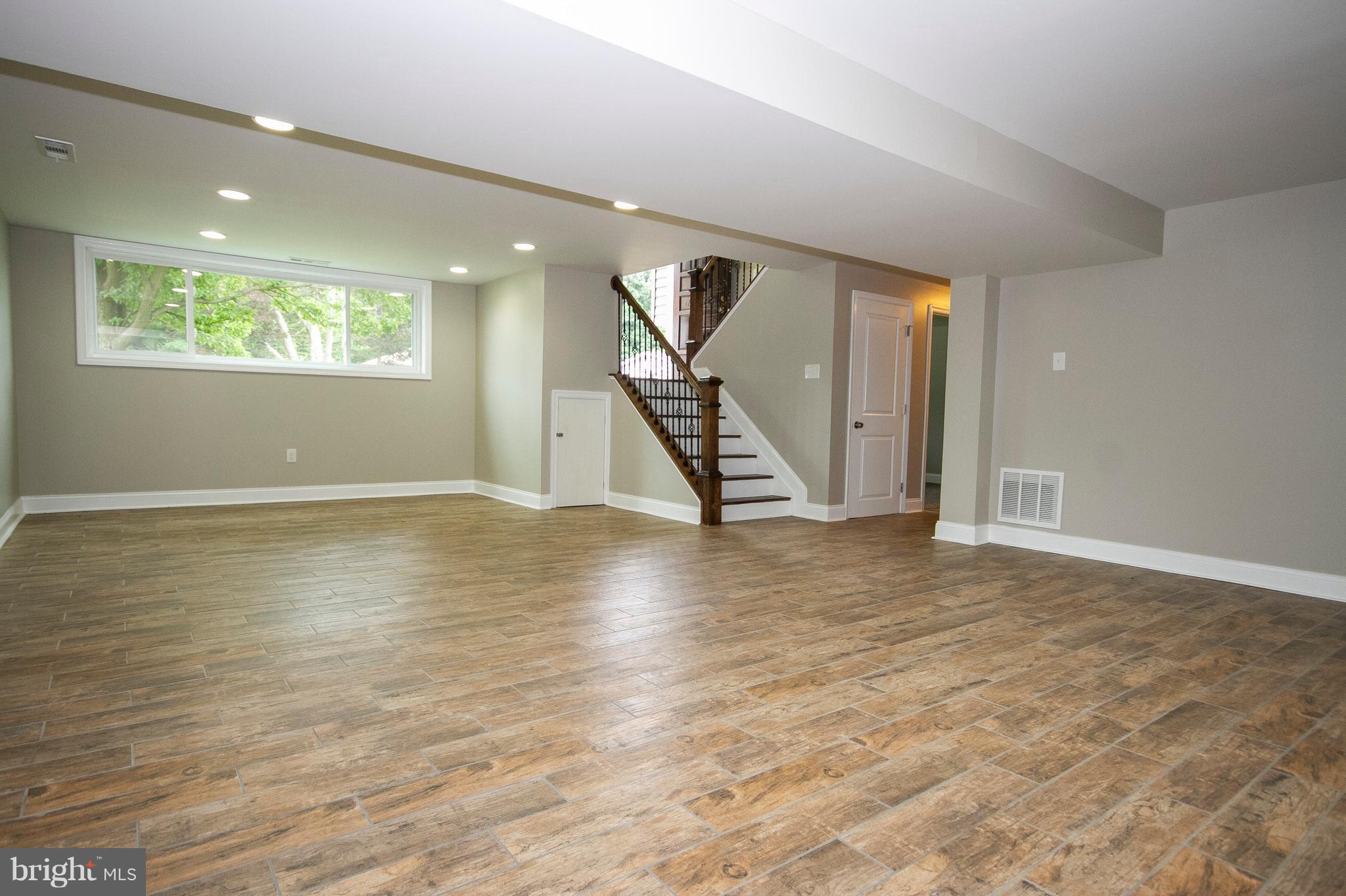 7412 Prince George Road Baltimore, MD 21208 - Photo 14 of 22 an empty room with wooden floor staircase and a ceiling fan