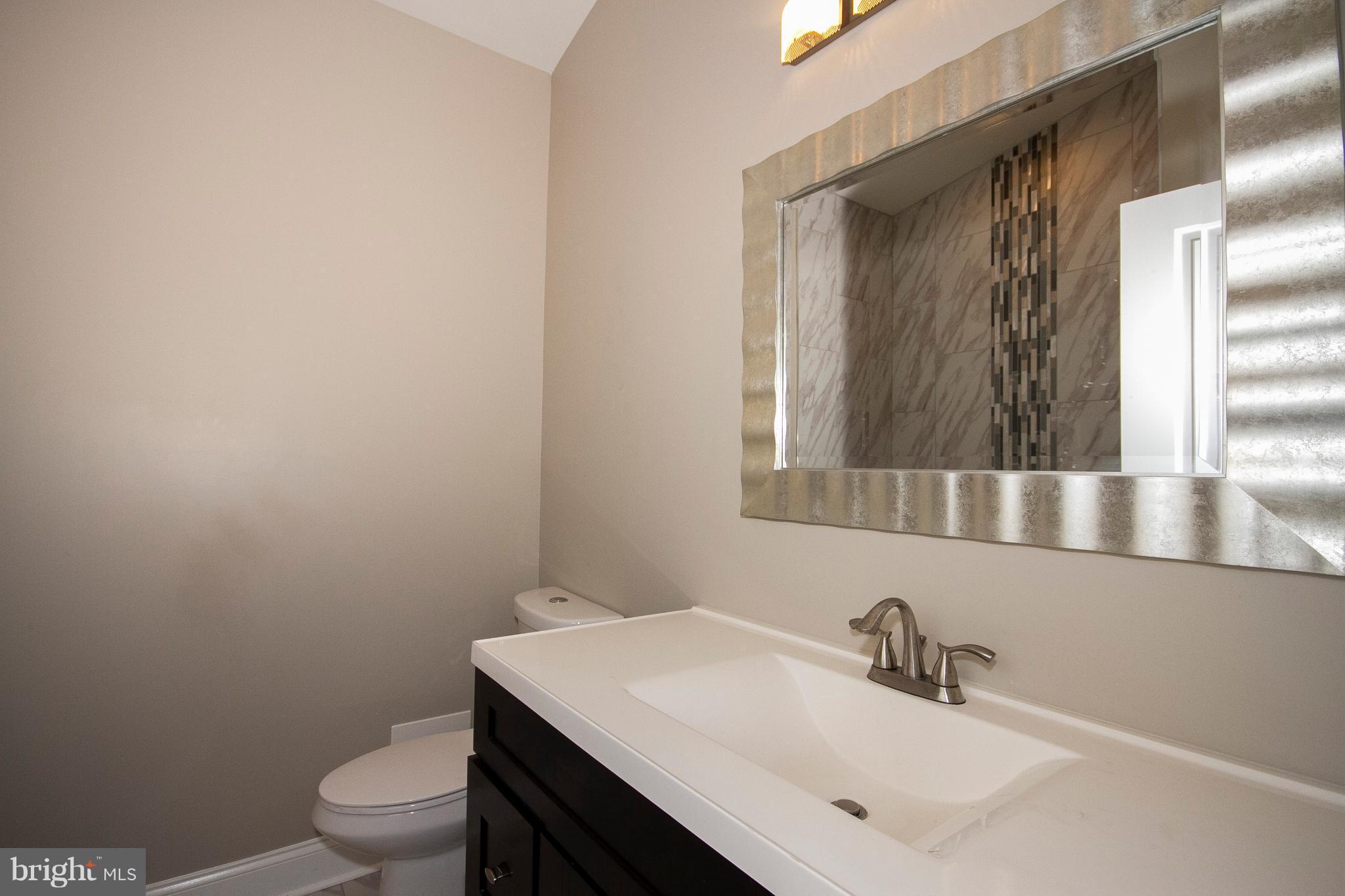 7412 Prince George Road Baltimore, MD 21208 - Photo 5 of 22 a bathroom with a sink a toilet and mirror