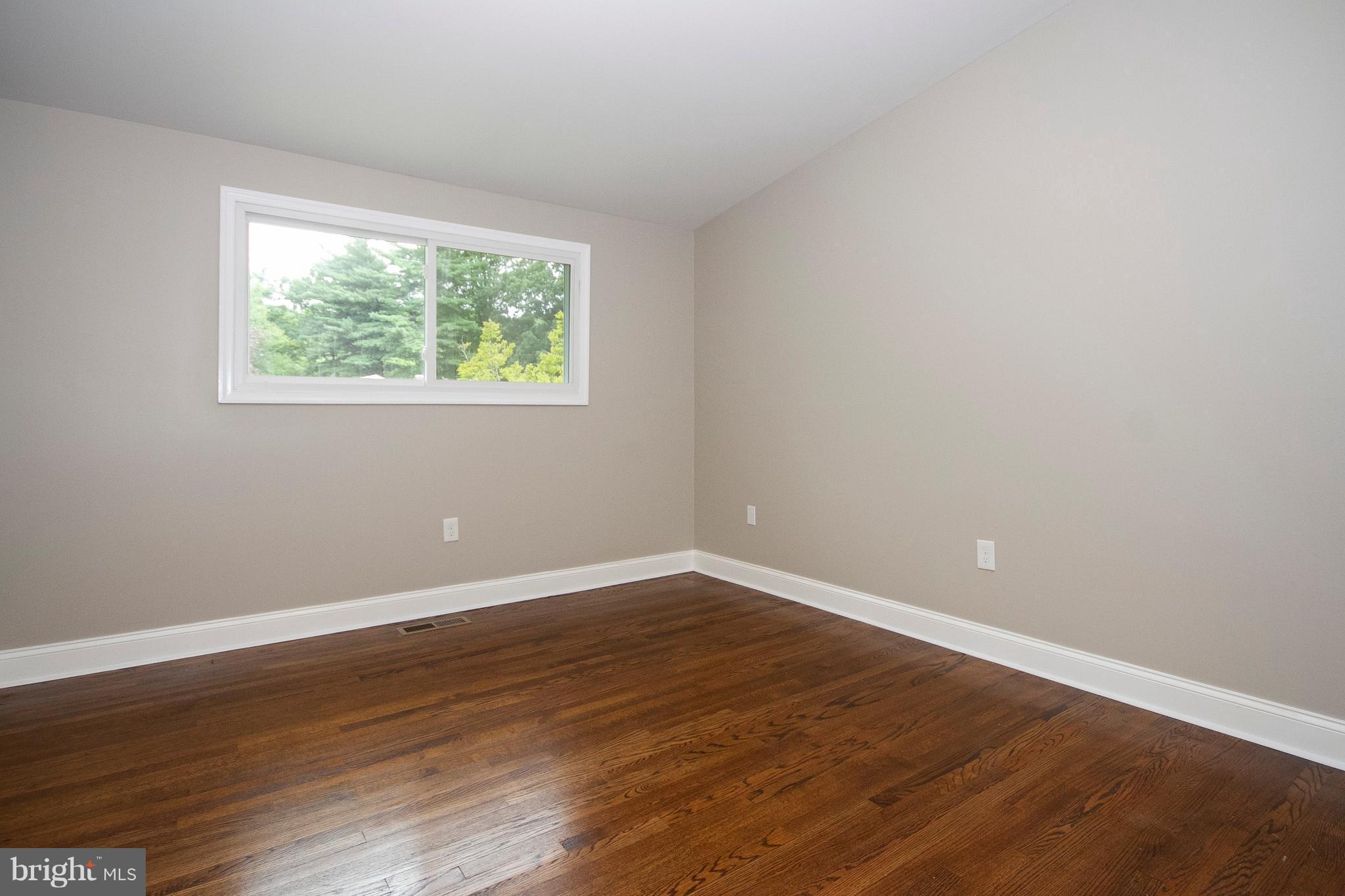 7412 Prince George Road Baltimore, MD 21208 - Photo 7 of 22 an empty room with wooden floor and windows