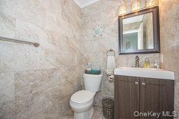 63 East Tiana Road Hampton Bays, NY 11946 - Photo 14 of 30 a bathroom with a granite countertop sink toilet and mirror