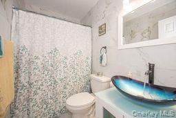 63 East Tiana Road Hampton Bays, NY 11946 - Photo 20 of 30 a bathroom with a toilet and a shower curtain