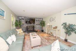63 East Tiana Road Hampton Bays, NY 11946 - Photo 6 of 30 a living room with furniture a fireplace and potted plants