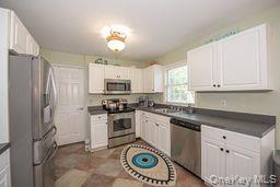 63 East Tiana Road Hampton Bays, NY 11946 - Photo 9 of 30 a kitchen with stainless steel appliances granite countertop a stove a sink dishwasher a refrigerator and cabinets with wooden floor
