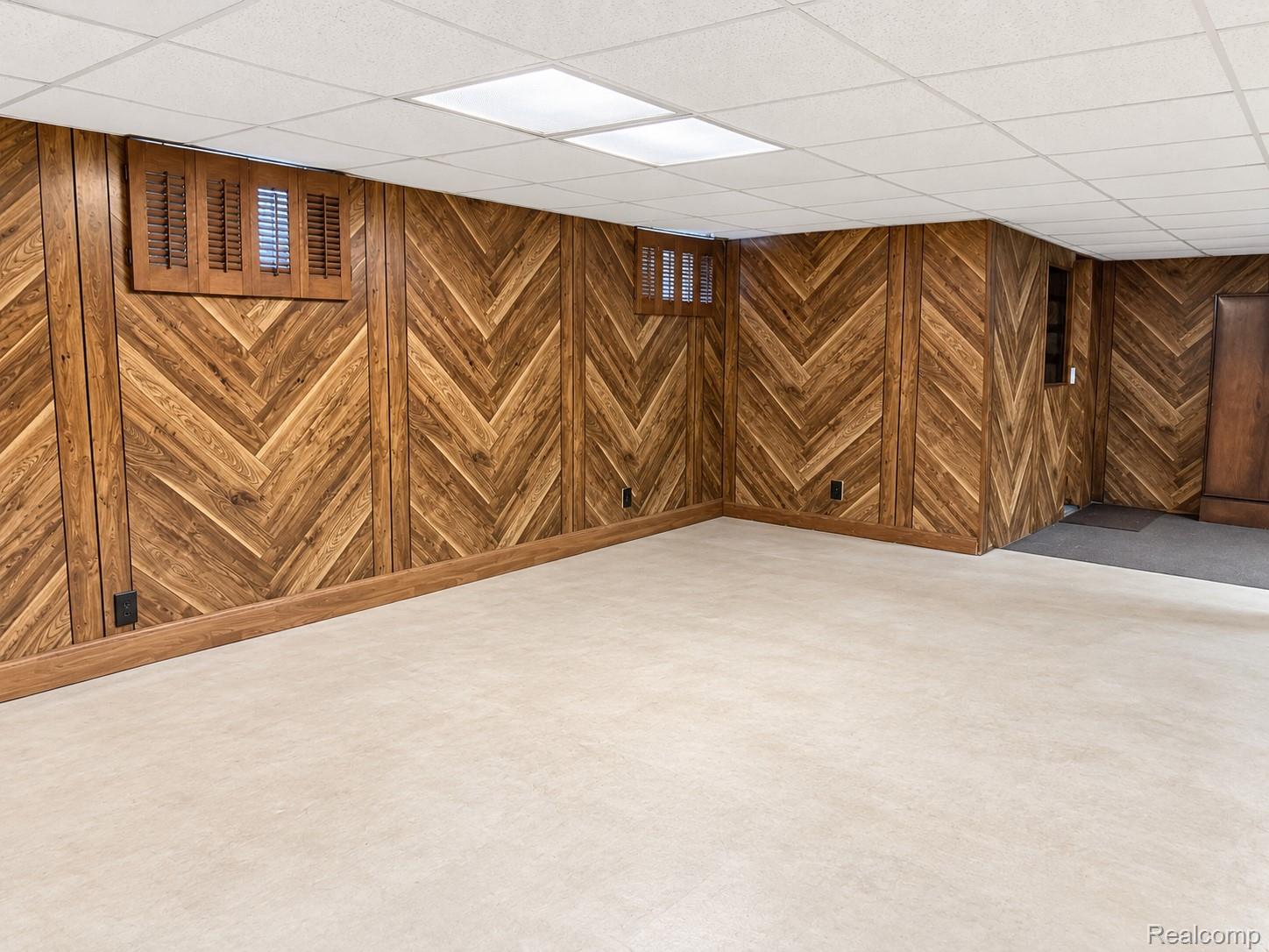 4529 Frazho Road Warren, MI 48091 - Photo 4 of 9 Wood-paneled walls with a herringbone pattern, drop ceiling with integrated lighting, and light-colored carpeting