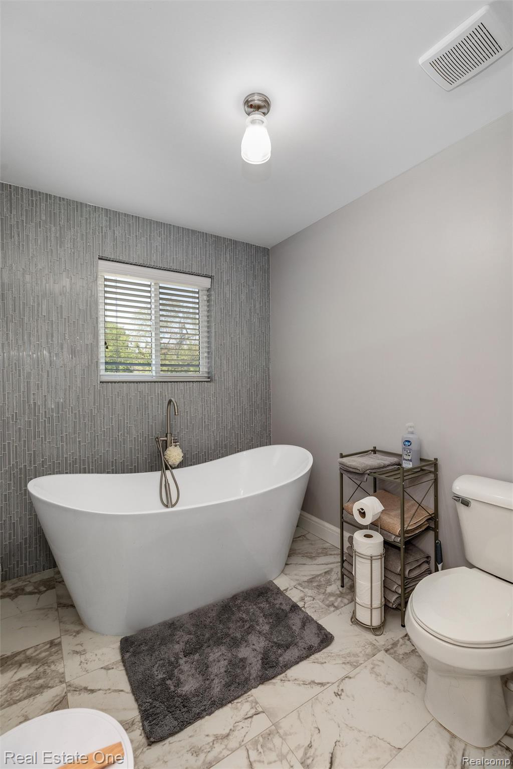 2983 28 Mile Road Washington, MI 48094 - Photo 29 of 54 Freestanding soaking tub with a floor-mounted faucet, complemented by a textured gray accent wall