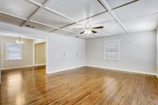 a view of an empty room with wooden floor and a window