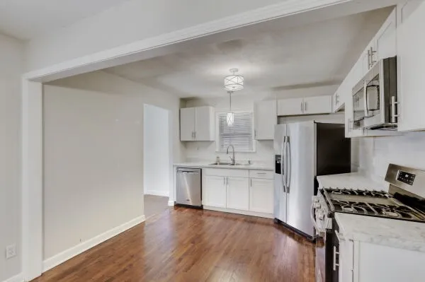 a kitchen with stainless steel appliances a refrigerator a stove a sink cabinets and wooden floor