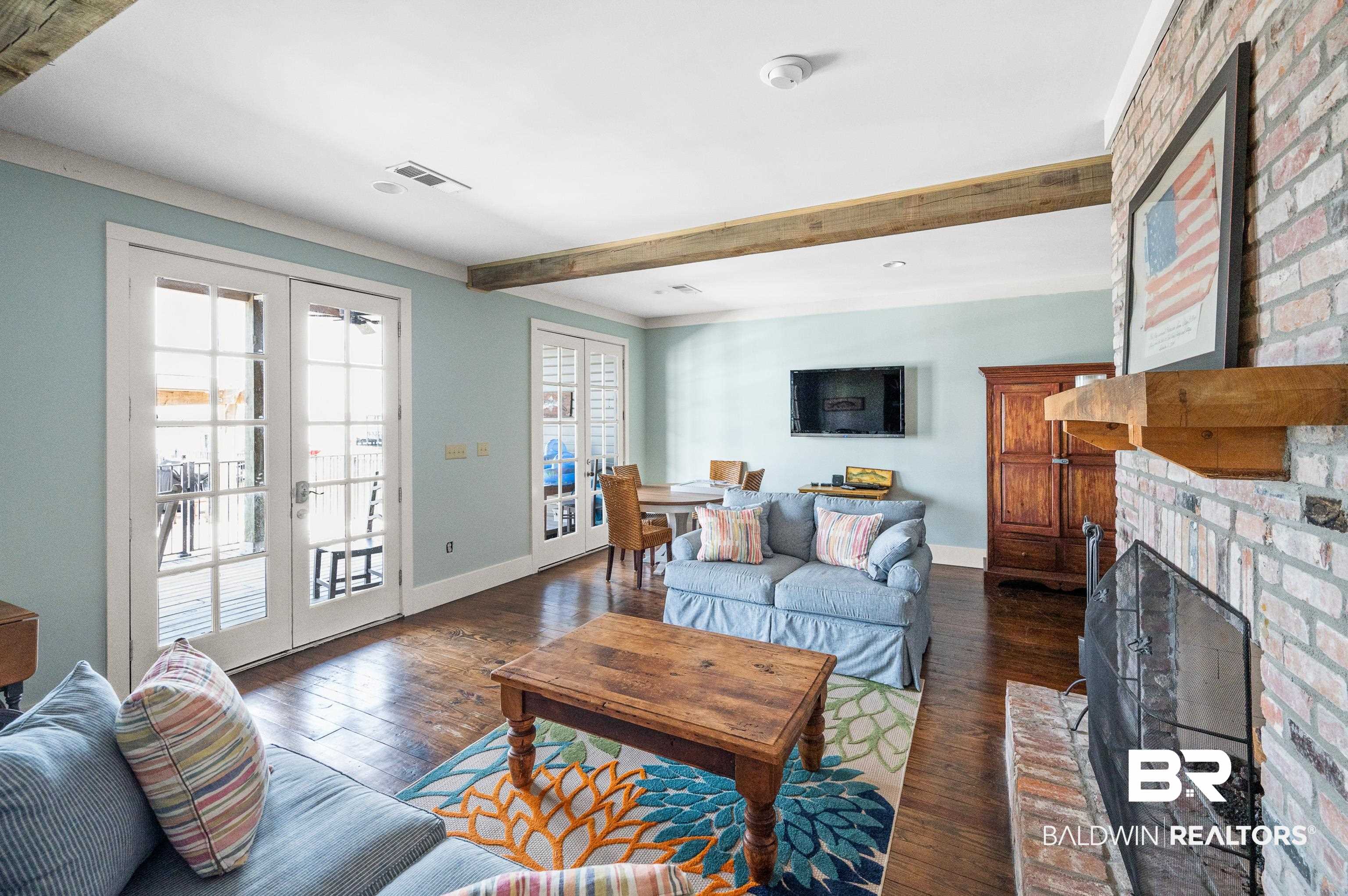 25773 Canal Road, Unit 10 Orange Beach, AL 36561 - Photo 37 of 40 Living room featuring a fireplace, beam ceiling, dark wood-type flooring, and french doors