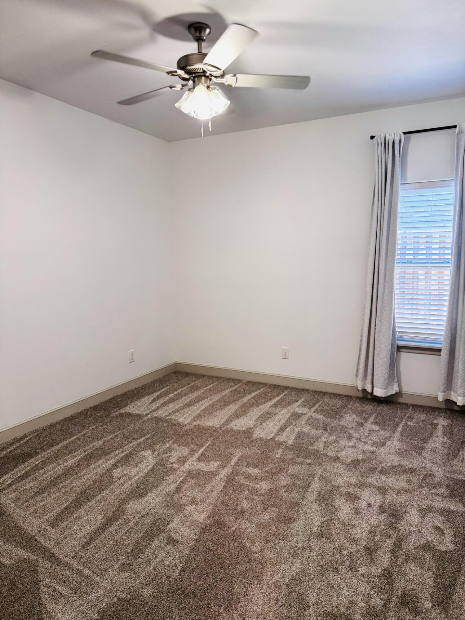 5615 115th Street Lubbock, TX 79424 - Photo 20 of 31 an empty room with a window and a ceiling fan