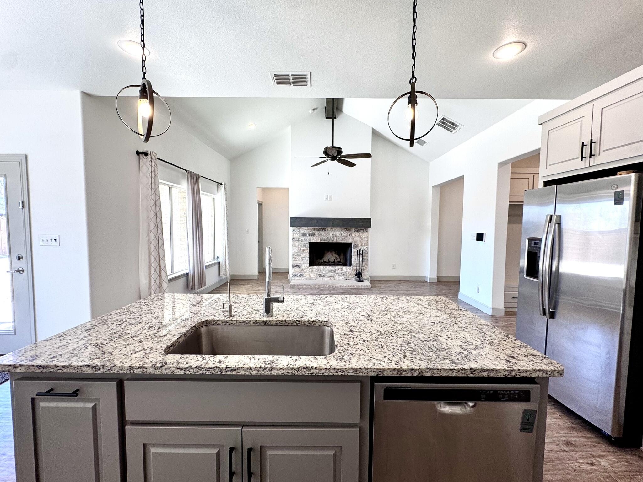 5615 115th Street Lubbock, TX 79424 - Photo 7 of 31 a kitchen with center island wooden floor and refrigerator