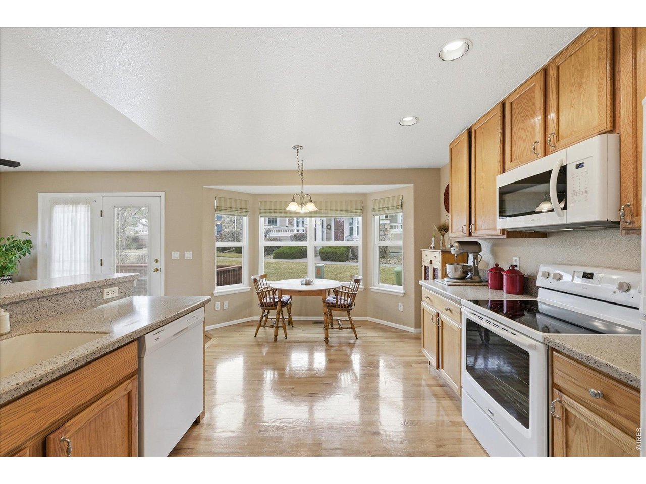 6227 Secrest Lane Arvada, CO 80403 - Photo 26 of 47 a kitchen with stainless steel appliances granite countertop a stove a sink dishwasher a microwave oven with cabinets and wooden floor