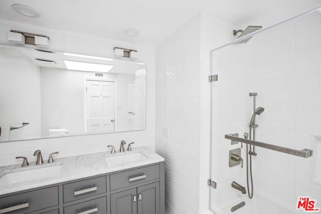 16636 Calneva Drive Encino, CA 91436 - Photo 12 of 18 a bathroom with a granite countertop sink a mirror and a shower