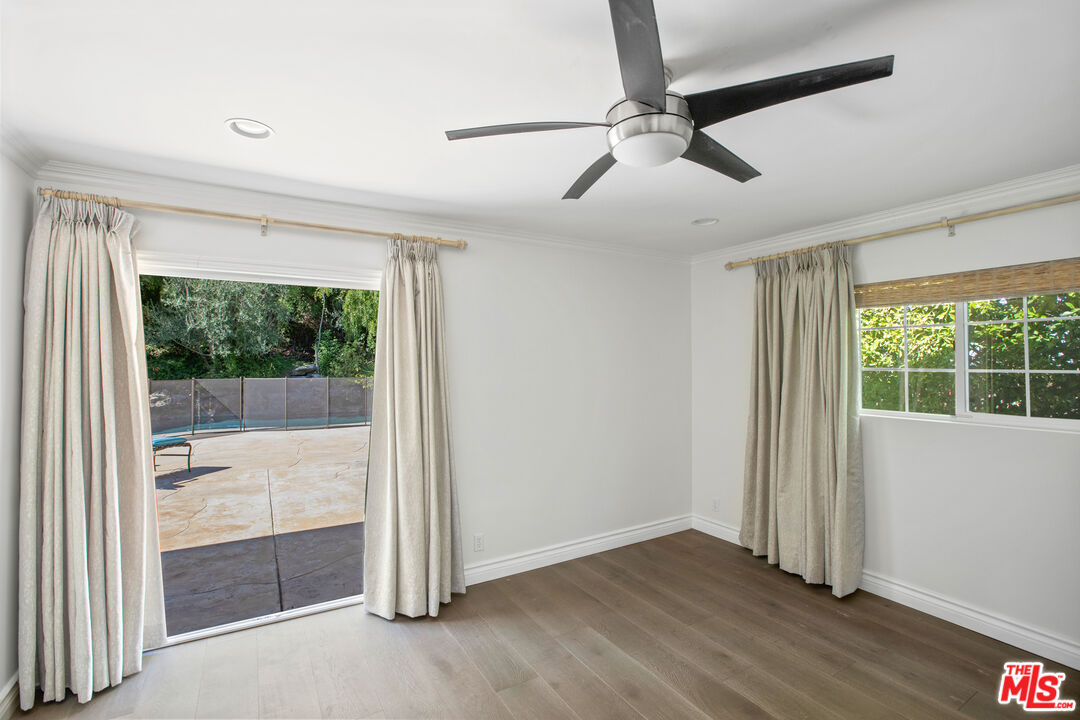 16636 Calneva Drive Encino, CA 91436 - Photo 9 of 18 an empty room with wooden floor fan and windows