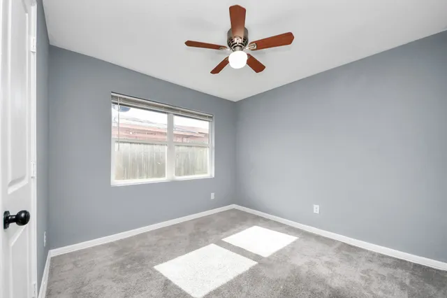 a view of a room with a ceiling fan and window
