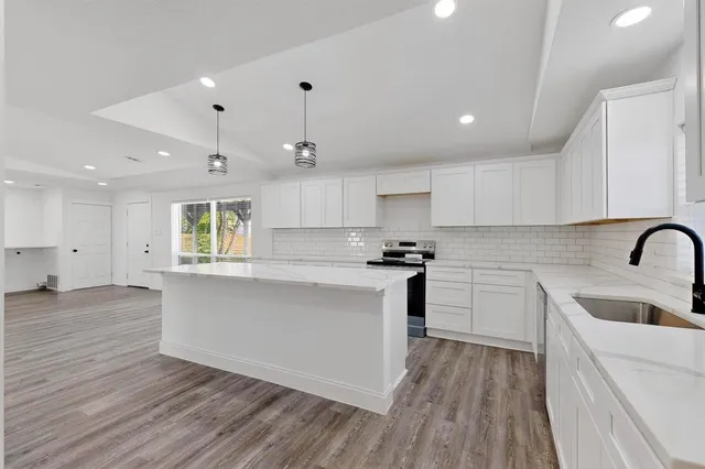 a kitchen with stainless steel appliances granite countertop a sink a stove and a wooden floors