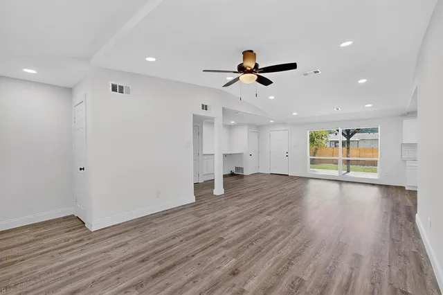 a view of empty room with wooden floor and ceiling fan