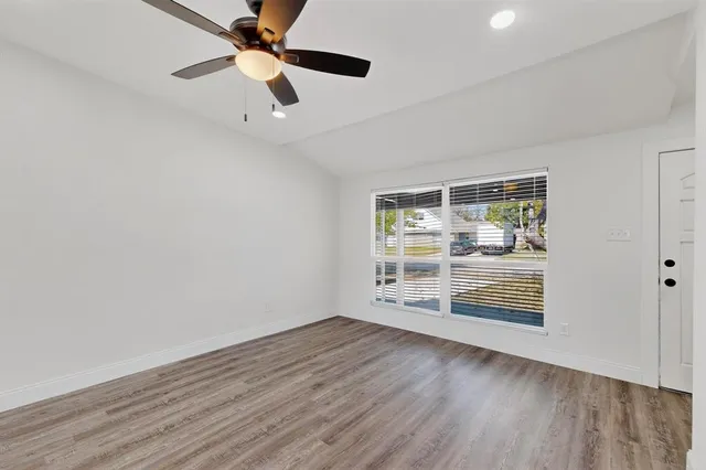 an empty room with wooden floor ceiling fan and windows