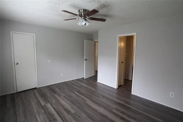 an empty room with wooden floor and a ceiling fan