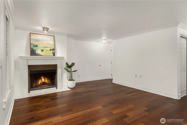 a view of an empty room with wooden floor fireplace and a window