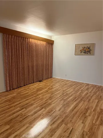 a view of a hallway to a room with wooden floor and stairs