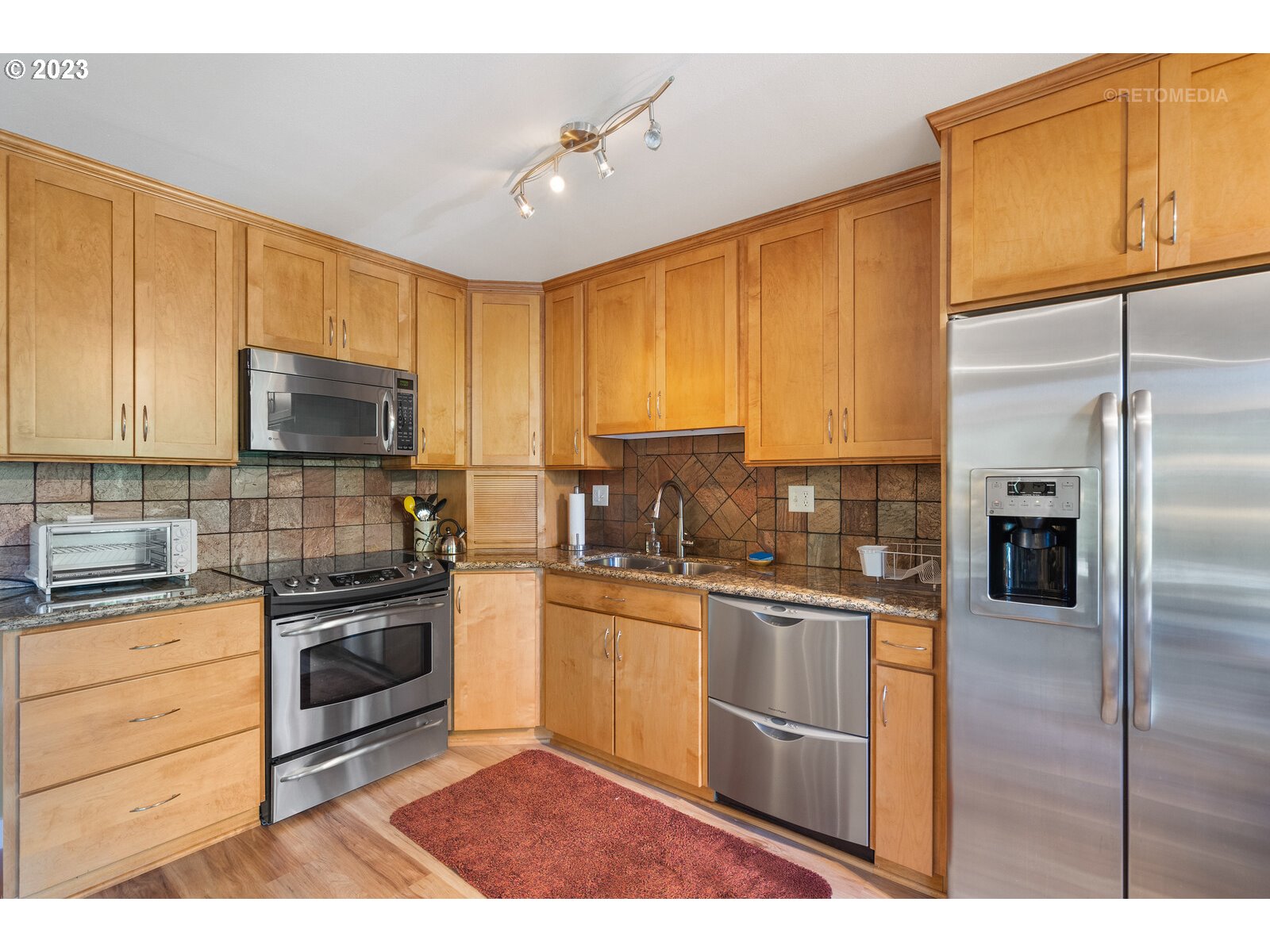 2021 Southwest Main Street, Unit 32 Portland, OR 97205 - Photo 10 of 38 a kitchen with stainless steel appliances granite countertop a stove top oven a sink dishwasher a refrigerator and cabinets with wooden floor