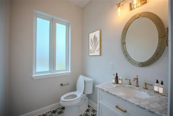 a bathroom with a granite countertop toilet a sink and a mirror