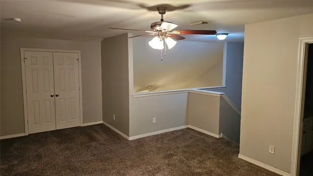 an empty room with a fan & a window