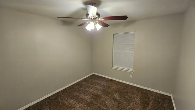 a view of an empty room and chandelier fan