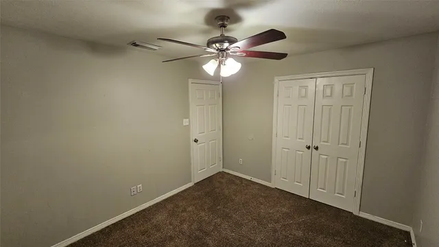 an empty room with a ceiling fan and a window