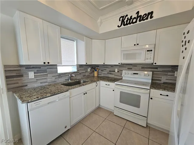 a kitchen with granite countertop white cabinets and white stainless steel appliances