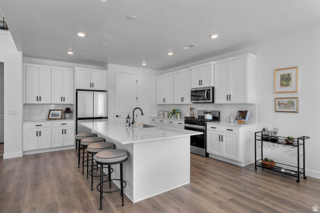 382 North Rhyolite Drive, Unit 111 Hurricane, UT 84737 - Photo 33 of 37 Modern kitchen featuring white shaker cabinetry, stainless steel appliances, a large center island with seating, recessed lighting, and wood-finish flooring