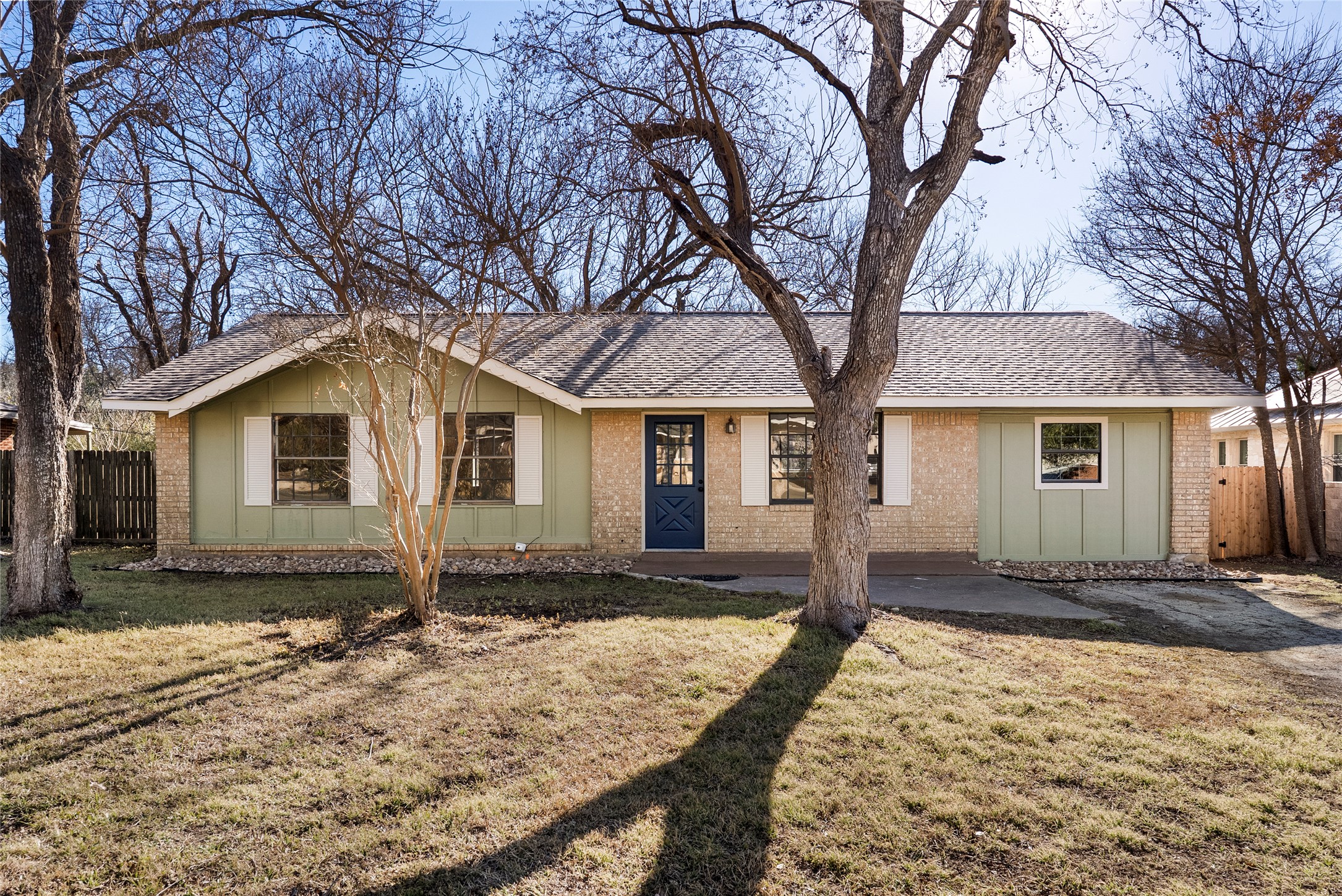 Single level home with board and batten siding, brick siding, and a shingled roof