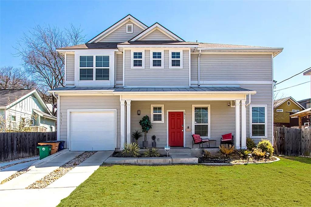 Traditional-style house featuring a porch, an attached garage, fence, and a front yard