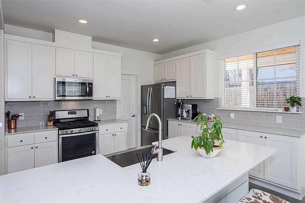 1311 Fort Branch Boulevard Austin, TX 78721 - Photo 12 of 27 Kitchen with a sink, decorative backsplash, appliances with stainless steel finishes, and white cabinets