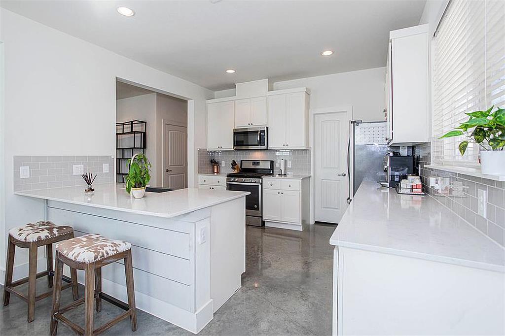 1311 Fort Branch Boulevard Austin, TX 78721 - Photo 8 of 27 Kitchen featuring a kitchen breakfast bar, appliances with stainless steel finishes, a peninsula, and white cabinetry