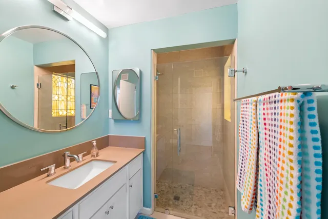 a bathroom with a sink a mirror a vanity and shower