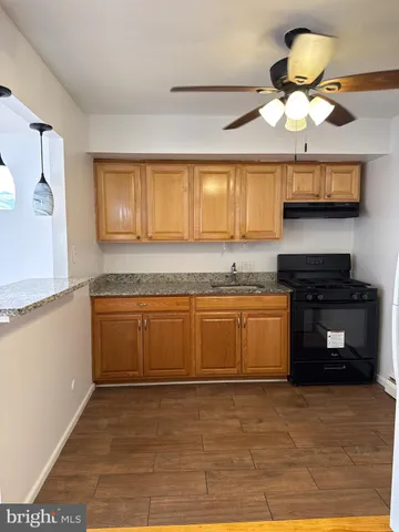 a kitchen with granite countertop a stove cabinets and wooden floor