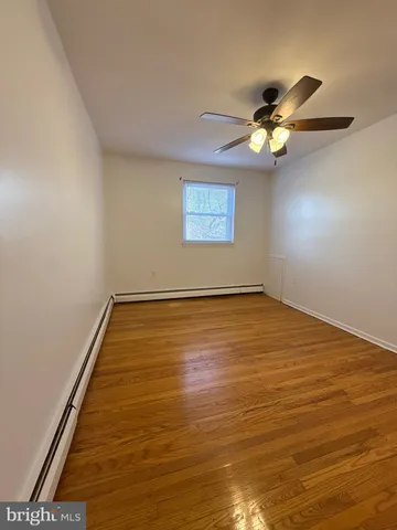 an empty room with a ceiling fan and wooden floor